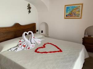 Dos toallas en una cama con un corazón. en Anna Apartment en Positano
