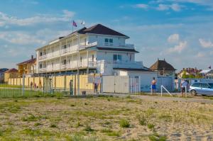 a building on the beach with people standing in front of it at Family Hotel Happy INN in Zatoka