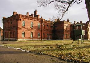 un grand bâtiment en briques avec un arbre devant lui dans l'établissement Karosta Prison, à Liepāja