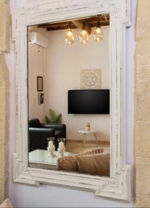 un miroir reflétant un salon avec un canapé et une télévision dans l'établissement Diogenis Residence Euphoria, à Arménoi