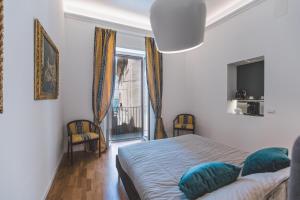 a bedroom with a bed with blue pillows and a window at Suites of the Royal Council in Siracusa