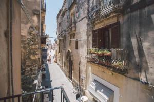 an alley with some plants on a balcony at Suites of the Royal Council in Siracusa