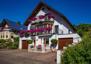 ein weißes Haus mit lila Blumen auf den Balkonen in der Unterkunft Ferienwohnung Wagner 4 Sterne in Neef