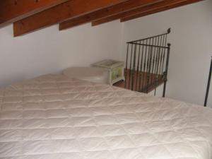 Cama blanca en habitación con escalera en CASA PUTIFIGARI, en Putifigari
