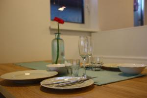 une table avec des assiettes et des verres et une fleur rouge dans un vase dans l'établissement APARTMENTS 1A RIBNO - BLED, à Bled