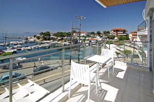 uma varanda com cadeiras brancas e vista para uma marina em Aqua Marine 2 em Neos Marmaras