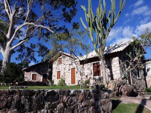 a stone house with a stone wall and trees at Oforasteiro in Mucugê