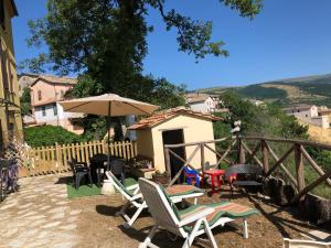 a patio with chairs and a table and an umbrella at Casavacanze Ciaspole E Uva in Fiastra