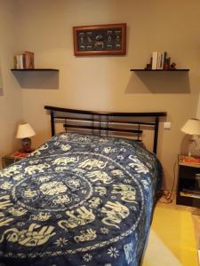 a bedroom with a bed with a blue and white comforter at Vacances Paisibles Sur La Côte Fleurie. in Trouville-sur-Mer