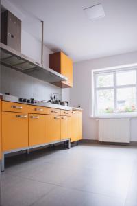 pusta kuchnia z pomarańczowymi szafkami i oknem w obiekcie Hostel 55 - darmowy parking we Wrocławiu
