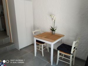 une petite table avec deux chaises et un vase avec des fleurs. dans l'établissement Studio Sausset les pins, à Sausset-les-Pins 4 autres photos