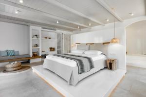 a white bedroom with a large bed and a bathroom at Arco Solium Suites in Adamas