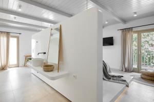 a bathroom with white walls and a large mirror at Arco Solium Suites in Adamantas