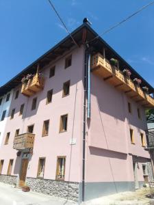 ein großes rosafarbenes Gebäude mit zwei Balkonen darauf in der Unterkunft B&B Cedavécia in Comèlico Superiore