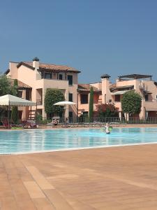 a person swimming in a swimming pool with buildings in the background at Esclusivo trilocale con piscina al Garda Resort Village in Peschiera del Garda