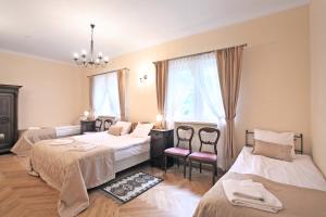 a bedroom with three beds and a chandelier at Pałac w Dębinie in Krzeszkowice