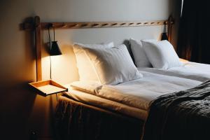 Hotel Isbolaget في Donsö: سرير بمخدات بيضاء تجلس بجانب لمبة