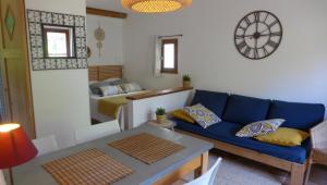 uma sala de estar com um sofá azul e uma cama em Les Mirabelles em Mirabel-aux-Baronnies