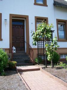 una casa con una puerta y un árbol delante de ella en Katharina Ferienwohnung am Eifelsteig en Neroth