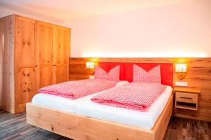 Schlafzimmer mit einem Bett mit roten und weißen Kissen in der Unterkunft Pension Unterstein in Schönau am Königssee