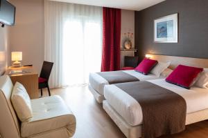 una habitación de hotel con 2 camas y una silla en Hotel La Chaumière, en Quillan