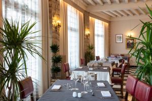 um restaurante com mesas, cadeiras e plantas em Hotel La Chaumière em Quillan