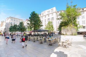 a group of people walking down a street with tables and chairs at Résidence La Source in Toulon