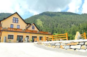 un grande edificio giallo con una montagna sullo sfondo di Pension Waldheim a Mauterndorf