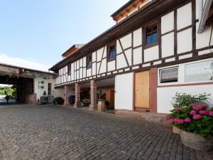 un antiguo edificio con flores en una calle adoquinada en Gästezimmer im Weingut Wolf, en Großkarlbach