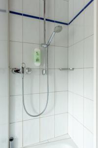 y baño con ducha y azulejos blancos. en Gästezimmer im Weingut Wolf en Großkarlbach