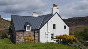 a white house with a black roof on a hill at Cruachan Guest House in Stoer