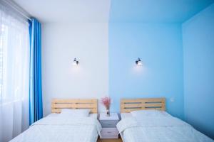 Duas camas num quarto com paredes azuis em Murphy Youth Hostel Guilin em Guilin