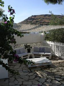 a patio with two white benches and a white fence at Vokamvilia Apartments in Kini