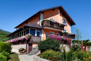 a house with flowers on the balconies of it at Plitvice Pension Perisic in Korenica