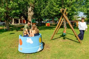 a family riding in a toy car on a playground at Hotel St Gregory Park in Rimini