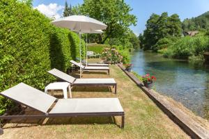 a group of lounge chairs and an umbrella next to a river at Haus Elisabeth in Seeboden