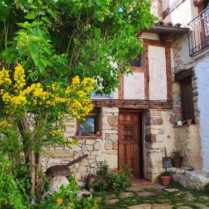 ein altes Steinhaus mit einer Holztür und Bäumen in der Unterkunft Casa rural LA LAGUNA in Laguna del Marquesado + 6 Fotos