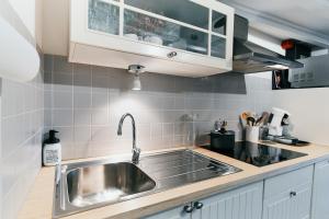 a kitchen with a stainless steel sink and white cabinets at Le Petit Gretedar in Malmedy