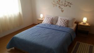 a bedroom with a bed with a blue blanket and two lamps at Apartman Ivanica in Jezera