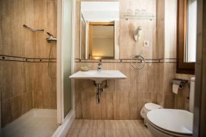 een badkamer met een wastafel, een toilet en een spiegel bij Hotel Victor in Rialp