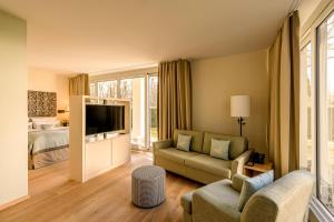 a living room with a couch and a television at Parkhotel Rothof in Munich