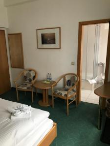 a hotel room with a bed and two chairs and a table at Pension Am Strand in Juliusruh