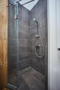 La salle de bains est pourvue d'une douche avec une porte en verre. dans l'établissement Ванный переулок Апартаменты Миконос, à Odessa
