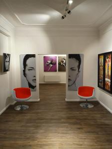 um quarto com duas cadeiras vermelhas e fotografias na parede em artHOTEL Bremen em Bremen