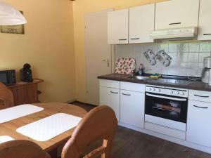a kitchen with white cabinets and a table and a sink at Ferienwohnung bi Klatt tu Hus in Wremen