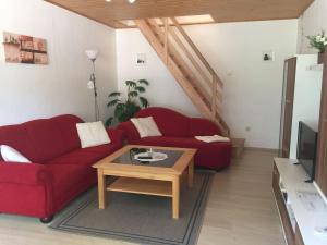 a living room with a red couch and a coffee table at Ferienwohnung bi Klatt tu Hus in Wremen