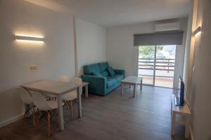 a living room with a table and a blue couch at Apartamentos Portinatx Sea View in Portinatx