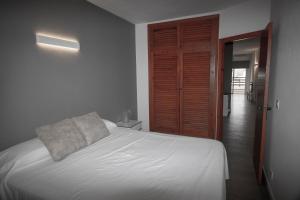 a bedroom with a white bed and a wooden door at Apartamentos Portinatx Sea View in Portinatx