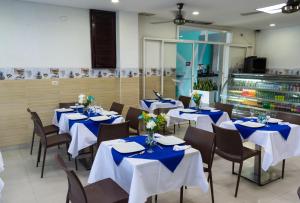 a dining room with tables and chairs with blue napkins at Hotel Medellín Rodadero in Santa Marta