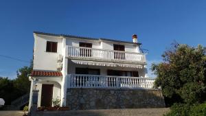 a white house with a balcony on top of it at Apartman Ivanica in Jezera